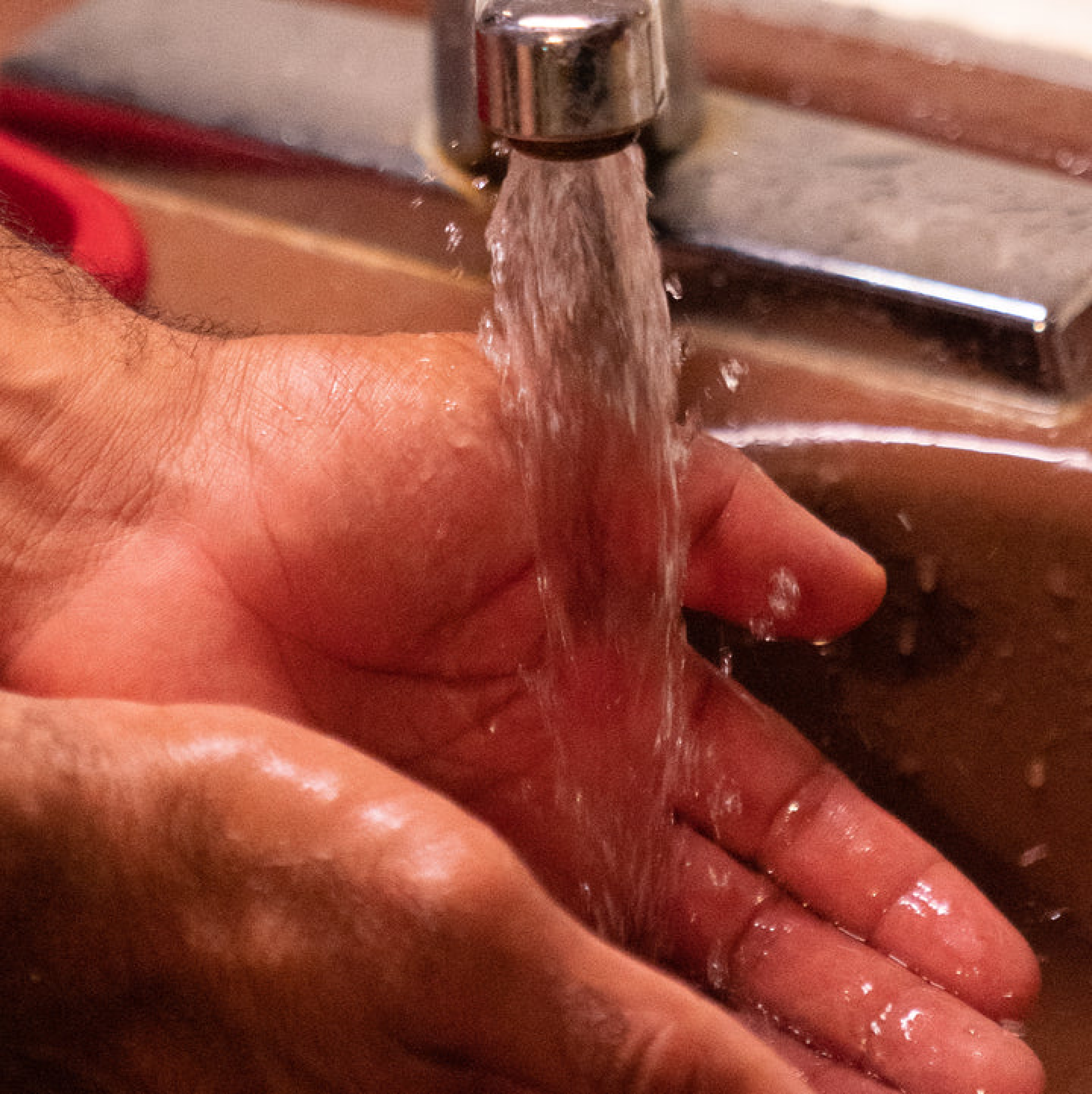 Close-up of hands being washed under running tap water for hygiene and hydration preparation.